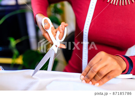 afro american woman with turban over head and silver ethnic colorful jewelry in tailor workshop 87185786