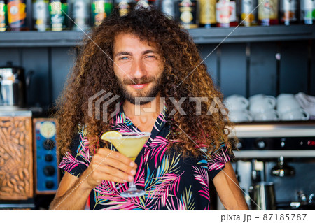long curly haired mixed race man barman making beverage alcoholic drink at beach shack in tropic 87185787