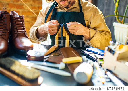 skilled shoemaker make a leather shoes in workshop skilled shoemaker make a leather shoes in workshop 87186471