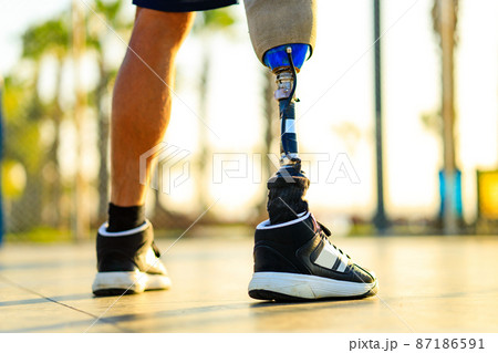 disabled athlete man with prosthetic walking at the beach outdoors at sunset disabled athlete man with prosthetic walking at the beach outdoors at sunset 87186591