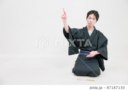 着物を着た男性が正座をして空間を指さす 87187130