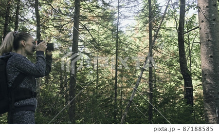 Traveler photographing scenic view in forest. One caucasian woman shooting nice magic look. Girl take photo video on dslr mirrorless camera. Traveler photographing scenic view in forest. One caucasian woman shooting nice magic look. Girl take photo video on dslr mirrorless camera. 87188585