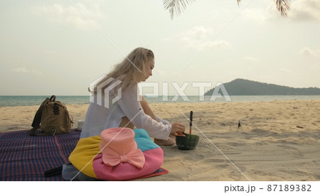 The cheerful woman in holding and eating slices of watermelon on tropical sand beach sea. Portrait attractive girl spend summer weekend. 87189382