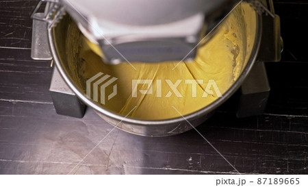 Mixing dough for bread baking with professional kneader spiral machine at the manufacturing. The dough is kneaded for burgers. Mixing dough for bread baking with professional kneader spiral machine at the manufacturing. The dough is kneaded for burgers. 87189665