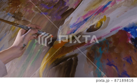 Artist designer draws an eagle on the wall. Craftsman decorator paints picture with acrylic oil color. Painter painter dressed in paint coat. Indoor. Artist designer draws an eagle on the wall. Craftsman decorator paints picture with acrylic oil color. Painter painter dressed in paint coat. Indoor. 87189816
