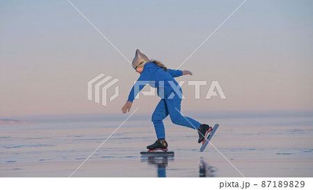The child train on ice professional speed skating. The girl skates in the winter in sportswear, sport glasses, suit. Outdoor slow motion. The child train on ice professional speed skating. The girl skates in the winter in sportswear, sport glasses, suit. Outdoor slow motion. 87189829
