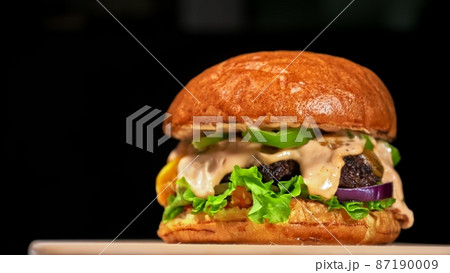 Craft burger is cooking on black background. Consist: sauce salsa, lettuce, red onion, pickle, cheese, chilli green pepper, bun, marbled meat beef. Craft burger is cooking on black background. Consist: sauce salsa, lettuce, red onion, pickle, cheese, chilli green pepper, bun, marbled meat beef. 87190009