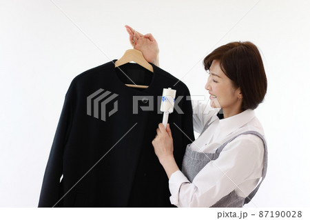 衣類に付いたほこりを取る女性 87190028