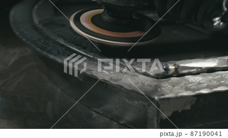 Forge workshop. Smithy manual production. Polish metal with an angle grinder with an abrasive nozzle. Polishing iron. 87190041