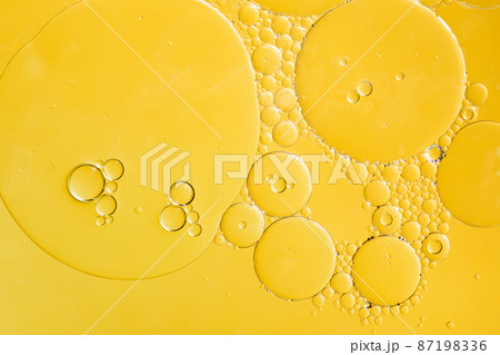 Golden yellow abstract oil bubbles or face serum background. Oil and water bubbles macro photography. 87198336