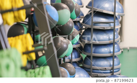 balls, dumbbells and balancing platforms in a gym. sport equipment next to a wall in a club. fitness and workout 87199623