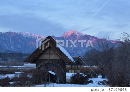 北杜市武川町、雪の積もった水車小屋と明け行く甲斐駒ケ岳 87199848