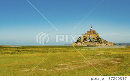 Stunning view of famous Le Mont Saint Michel tidal island on a bright sunny day with empty green fields, Normandy, Northern France 87200357