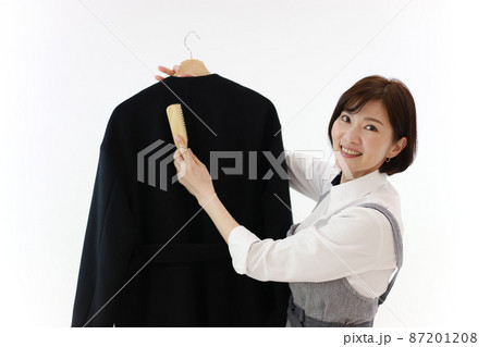 コートにブラシをかける女性 87201208