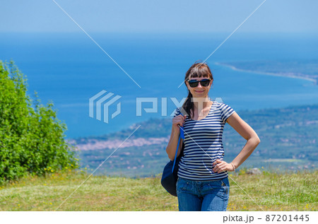 Young beautiful girl traveler with striped shirt, backpack and sunglasses looking at camera 87201445