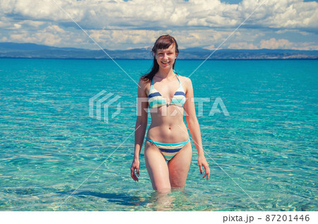 Young beautiful girl in bikini stay in turquoise water of Toroneos kolpos gulf Young beautiful girl in bikini stay in turquoise water of Toroneos kolpos gulf 87201446
