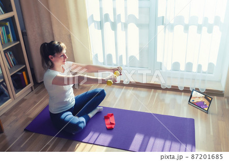 Young attractive woman in sports clothing doing workout at home 87201685