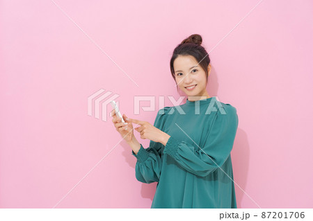 スマホを持つ女性　ピンク背景 87201706