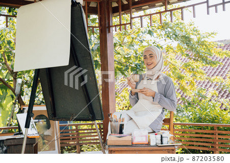 muslim Female artist painting on canvas drink tea 87203580