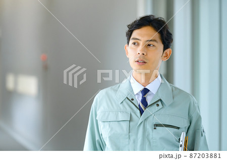 オフィスの廊下を歩く作業服を着た若いエンジニア オフィスの廊下を歩く作業服を着た若いエンジニア 87203881