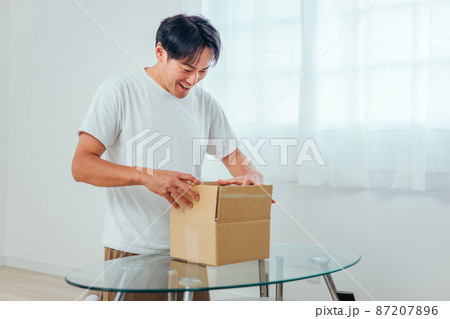段ボールを開ける男性（喜ぶ） 87207896