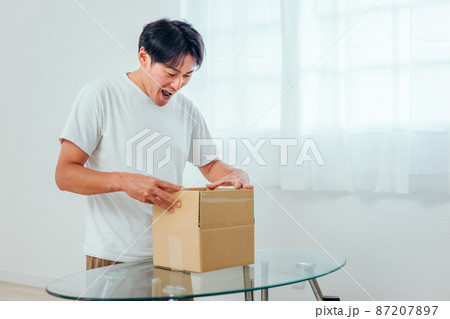 段ボールを開ける男性（喜ぶ） 87207897
