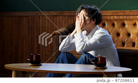 リビングで一人で落ち込む男性 87208611