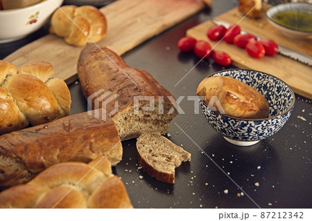 Feast, messy table. Bread in the shape of a braid. Sweet Challah. breakfast, side view. Cherry tomatoes and olive oil, Balsamic vinegar, Atlantic salt Feast, messy table. Bread in the shape of a braid. Sweet Challah. breakfast, side view. Cherry tomatoes and olive oil, Balsamic vinegar, Atlantic salt 87212342