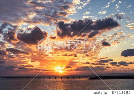 沖縄の海と桟橋の向こうに沈む真っ赤な夕日の写真素材 [87213199] - PIXTA