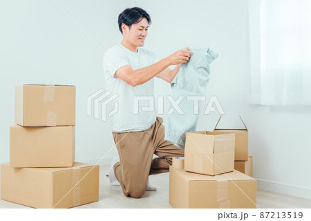 段ボールから洋服を出す男性 87213519