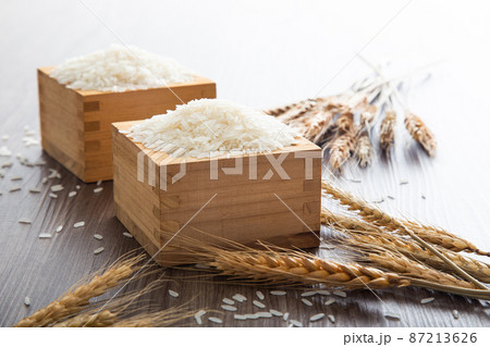 Uncooked dry Thai jasmine rice in box are overflow on wooden background Uncooked dry Thai jasmine rice in box are overflow on wooden background 87213626