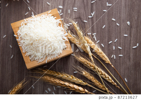 Uncooked dry Thai jasmine rice in box are overflow on wooden background Uncooked dry Thai jasmine rice in box are overflow on wooden background 87213627