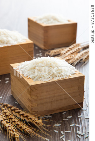 Uncooked dry Thai jasmine rice in box are overflow on wooden background Uncooked dry Thai jasmine rice in box are overflow on wooden background 87213628