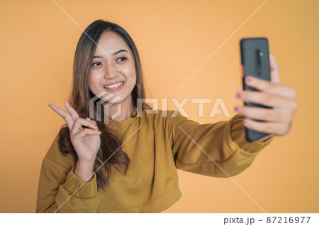 beautiful young woman selfie using phone camera with v sign beautiful young woman selfie using phone camera with v sign 87216977