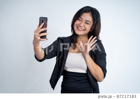 young woman make a video call with saying hello gesture young woman make a video call with saying hello gesture 87217183