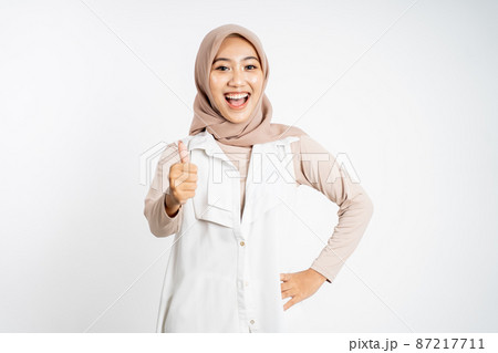 woman in hijab smiling with thumbs up while standing 87217711