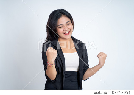 Excited asian woman clenching hands while celebrating success 87217951
