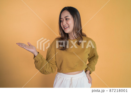 Young asian woman with hand gesture presenting something 87218001