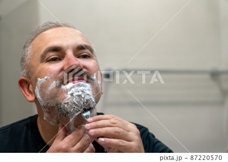 Middle aged handsome man shaving his beard in bathroom 87220570