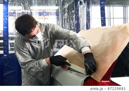 Mechanic covering car with paper before painting in auto repair service 87220681