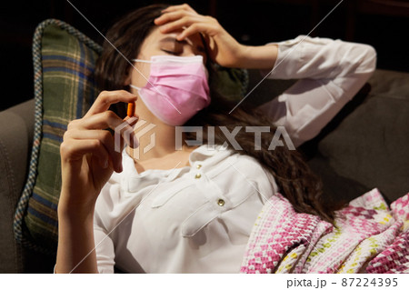 young woman on sofa covered with a blanket freezing blowing running nose got fever, caught, sick girl having influenza symptoms, flu or virus concept 87224395