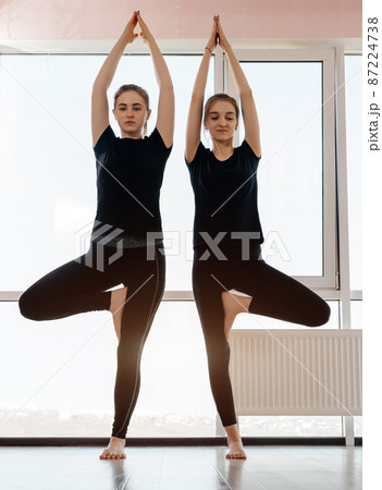 Two attractive girls practicing yoga concept, standing in Vrksasana exercise, Tree pose 87224738