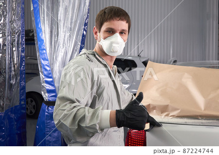 Mechanic covering car before painting in auto repair service 87224744