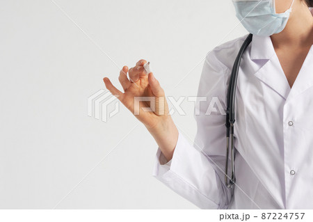 Doctor wearing face mask looking at measurement on medical thermometer over white background with copy space 87224757
