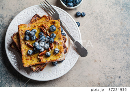 French toast with blueberries, pecan and maple syrup for breakfast on white plate. 87224936