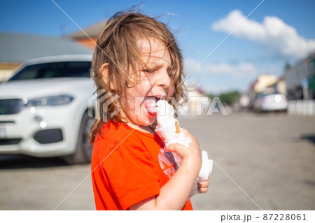 Cheerful child licking a vanilla ice cream on the beach 87228061