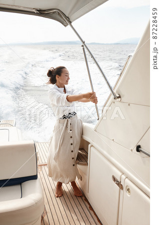 Woman in white shirt and beige skirt on yacht in the sea 87228459