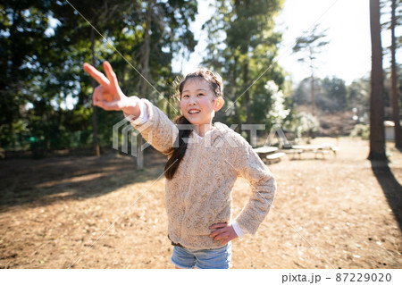 公園でピースサインをする少女 公園でピースサインをする少女 87229020