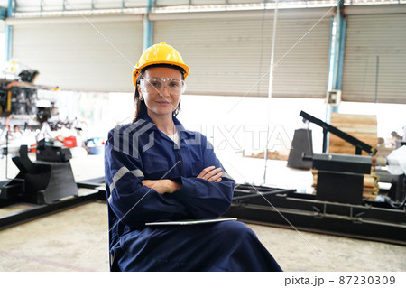 Female industrial worker working with manufacturing equipment in a factory Female industrial worker working with manufacturing equipment in a factory 87230309