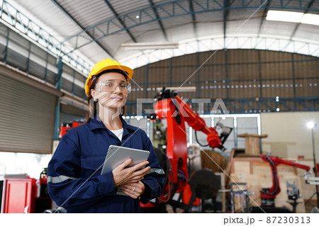 Female industrial worker working with manufacturing equipment in a factory Female industrial worker working with manufacturing equipment in a factory 87230313